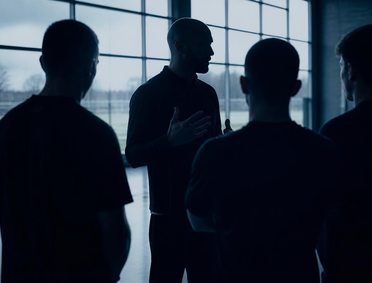 A coach speaking with a group of athletes
